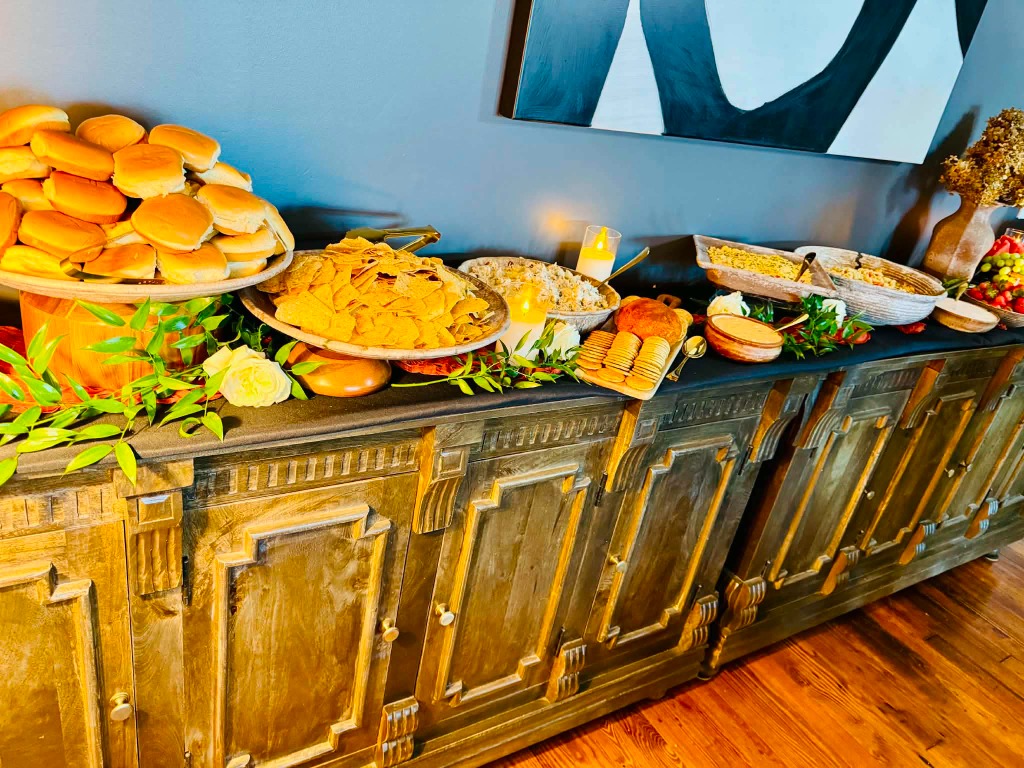Buffet station with chips, buns, pasta salad, and fruit